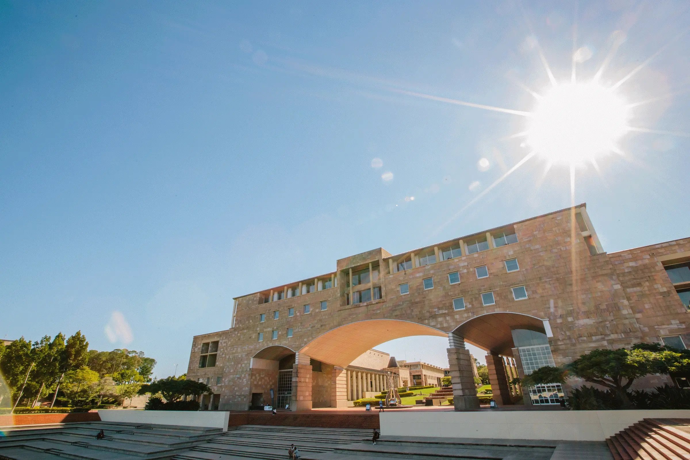 Universitätsgebäude der Bond University mit markanter Architektur unter blauem Himmel und strahlender Sonne