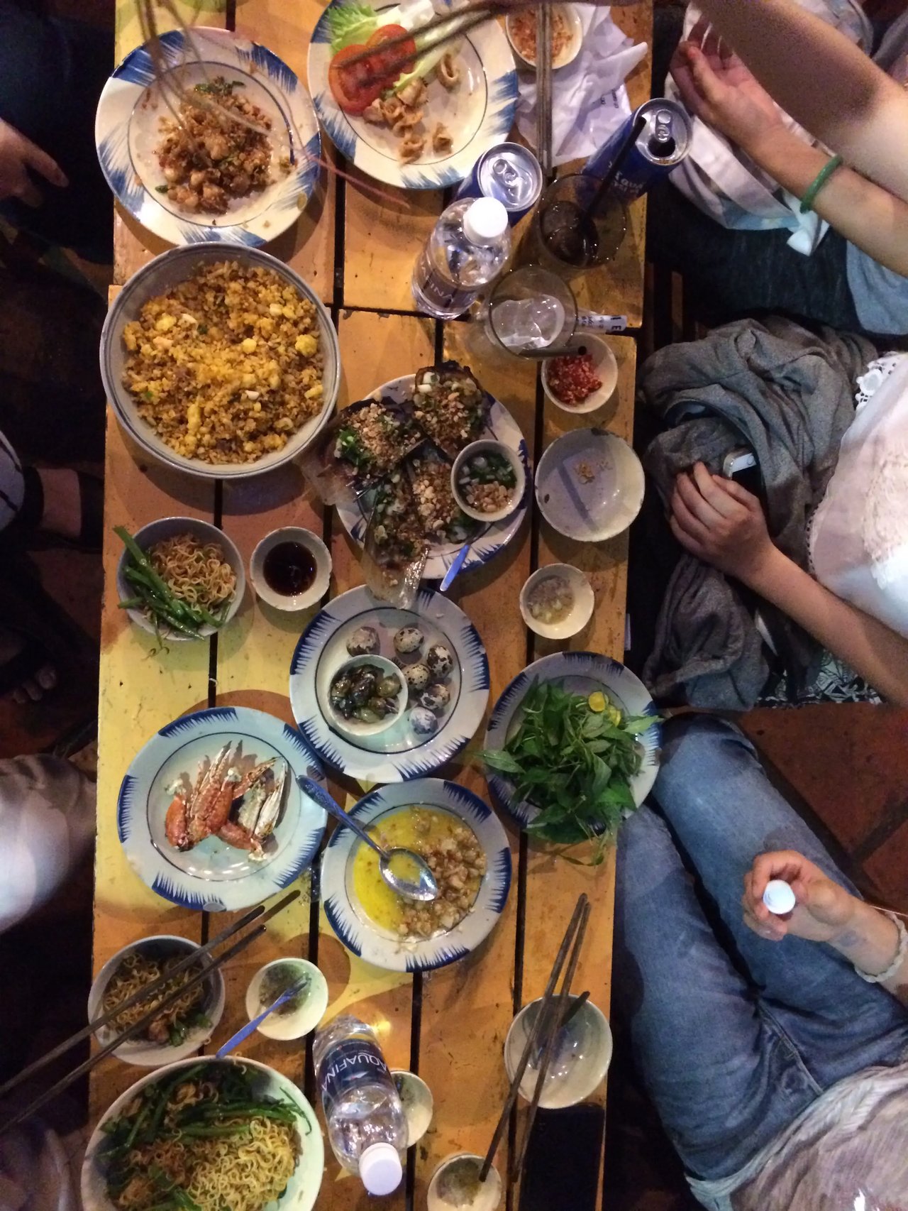 Ein gedeckter Tisch mit vietnamesischen Speisen, darunter Reis, Meeresfrüchte und Kräuter, während eines traditionellen Essens.