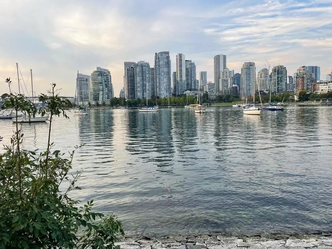 Beeindruckende Skyline von Vancouver mit reflektierendem Wasser im Vordergrund.