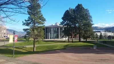 Campus der Thompson Rivers University in Kamloops, Kanada, umgeben von Bäumen und einem klaren Himmel.