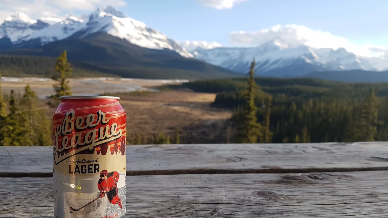 Bierdose auf einem Holztisch mit Blick auf schneebedeckte Berge in Kanada.